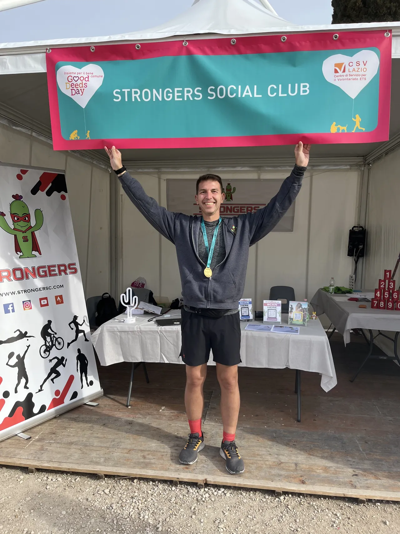 Uno Strongers a braccia alzate sotto lo striscione dello stand