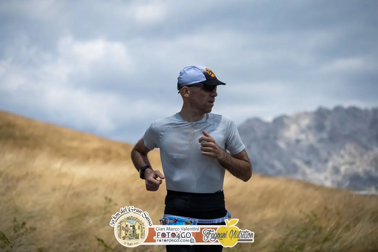 Raffaele corre sulla strada dell'altopiano, con le montagne del Gran Sasso sullo sfondo
