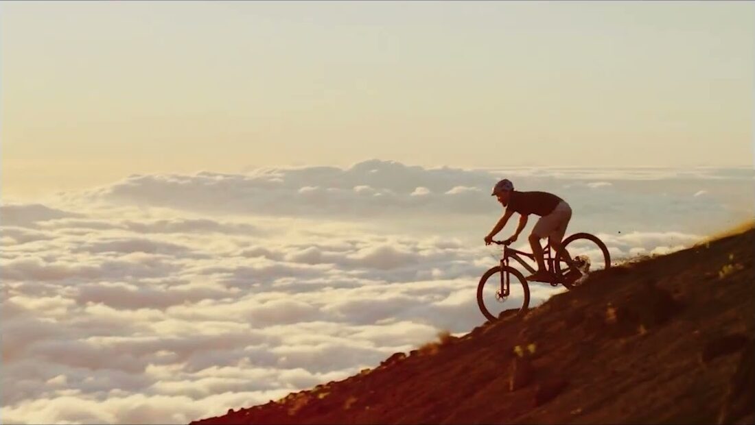 Atleta in mountain bike al tramonto sopra le nuvole