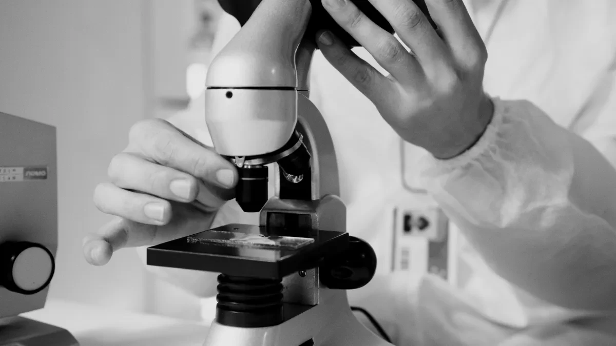 Giovane ricercatrice al microscopio in laboratorio oncologico, simbolo della precision oncology sul cancro al polmone